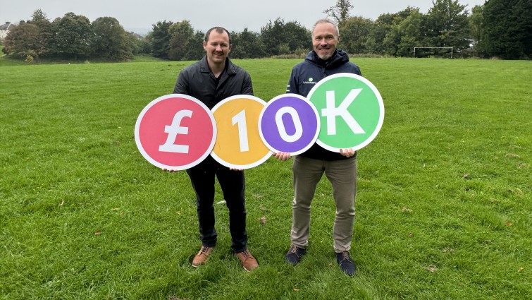 Two of the members of the Bothwell Futures Trust are pictured standing on the site they hope to acquire. togetehr they are holding four large circular props that say ten k.