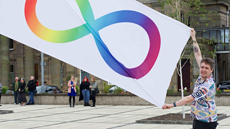 This image shows council employee John Whiteside with the Autism Pride flag outside council HQ