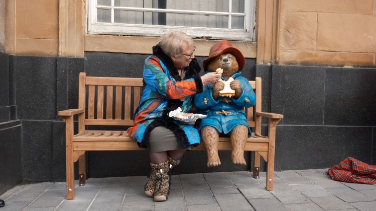 This image shows Provost Margaret Cooper feeding a statue of Paddington Bear a marmalade sandwich