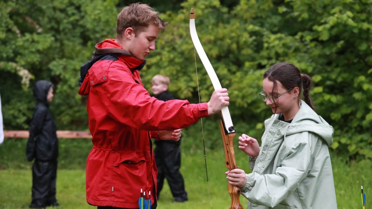 In this picture Rowan is on site at wiston lodge helping a primary school pupil practice archery.