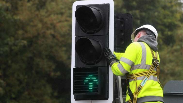 This image shows a roads worker working on a set of traffic lights