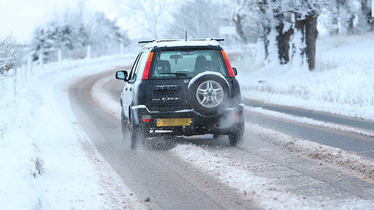 This is an image of a single vehicle driving along the road in snow. 