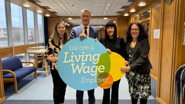 This image shows council staff holding a prop which says we are a Living Wage employer