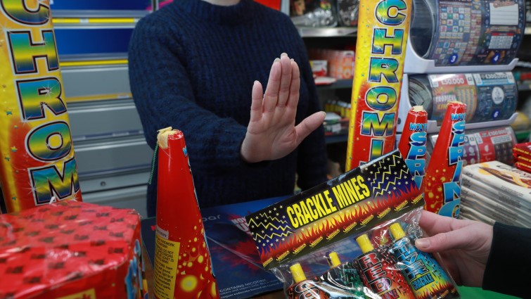 This is a staged image showing a retailer refusing to sell fireworks to a youth.