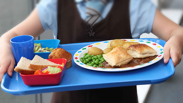 This is an image of a child holding school lunch on a tray.